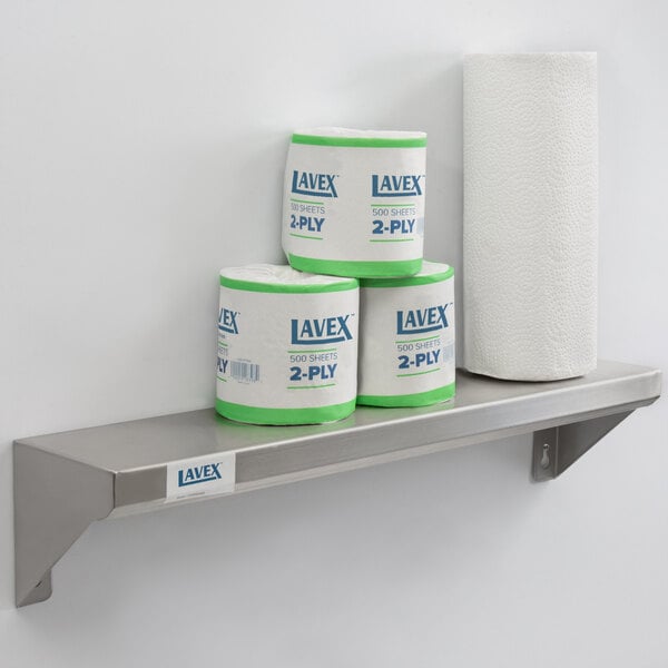 A Lavex stainless steel wall mount shelf holding rolls of toilet paper and a roll of paper towels.