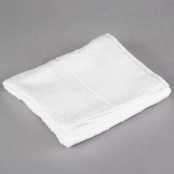 An Oxford white hand towel on a gray surface.