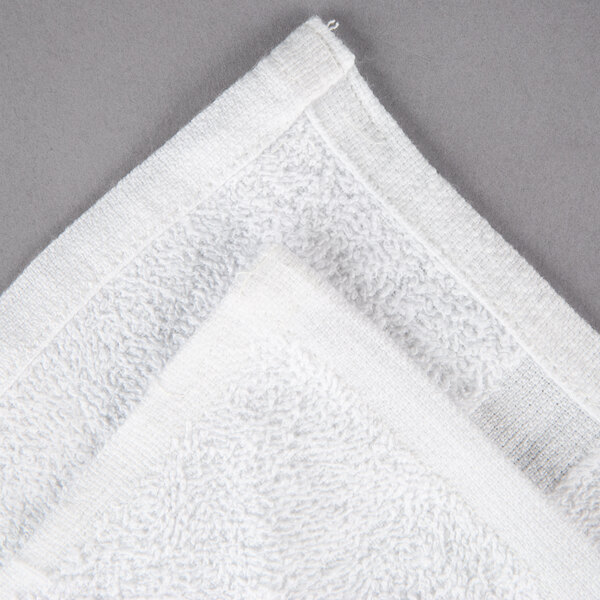 An Oxford white hand towel on a gray surface.