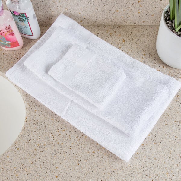 An Oxford white wash cloth on a counter with a pink and blue bottle.