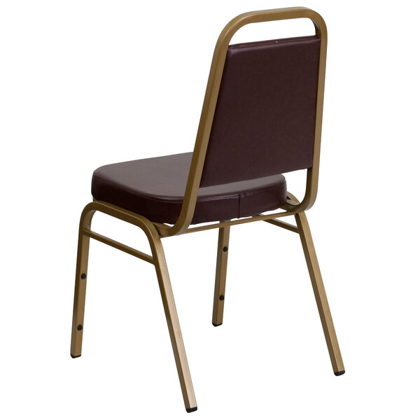 A brown Flash Furniture trapezoidal back banquet chair with a gold frame.