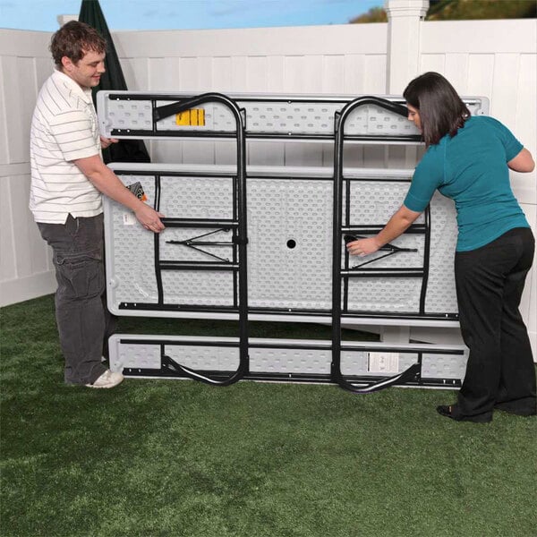 A man and woman assembling a Lifetime picnic table.