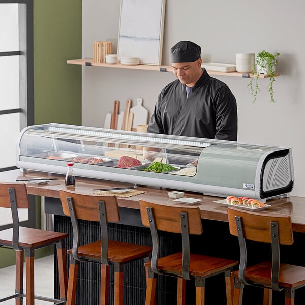 An Avantco refrigerated sushi display case on a countertop with food displayed inside.