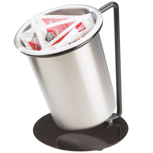 A black iron ring display with solid stainless steel cylinders holding packets on a hotel buffet counter.