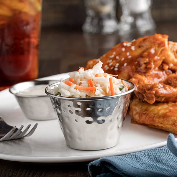 A plate of food with a bowl of coleslaw and chicken served with a Choice stainless steel sauce cup.