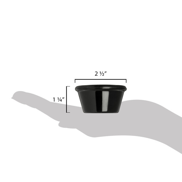 A hand holding a black Carlisle smooth melamine ramekin.