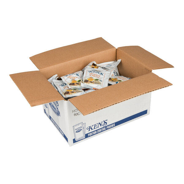 An open cardboard box containing multiple individual packets of Ken's Honey Dijon Mustard Dressing.
