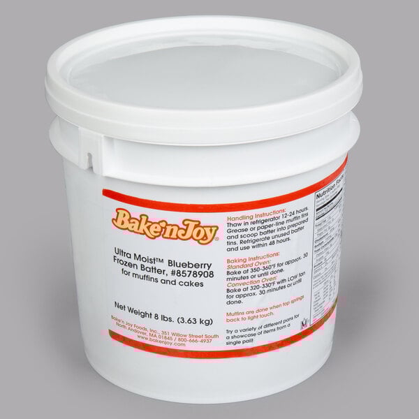 A white plastic bucket with a clear lid filled with Bake'n Joy blueberry muffin batter.