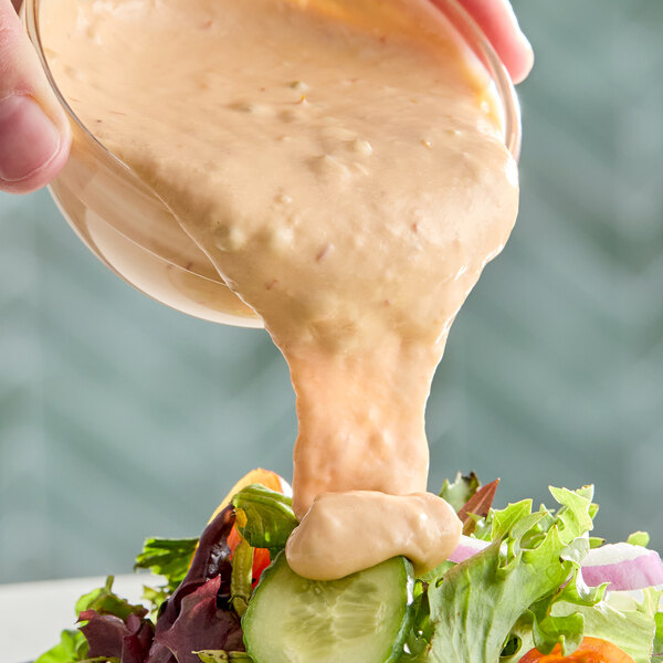 A creamy Thousand Island dressing being poured over a fresh salad.