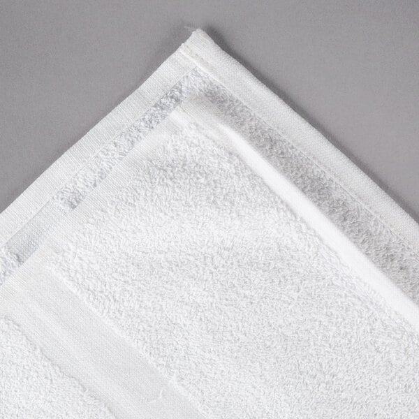 An Oxford white bath towel on a gray surface.