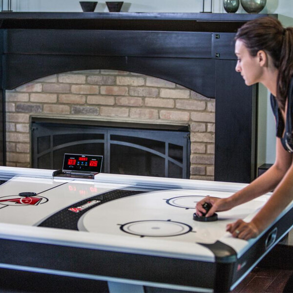 A woman playing air hockey on an Atomic air hockey table.