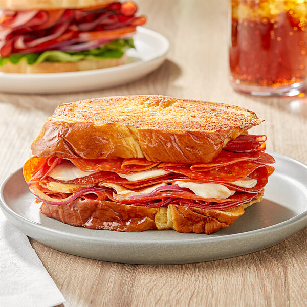 A sandwich with Margherita sandwich style sliced pepperoni and cheese on a plate.