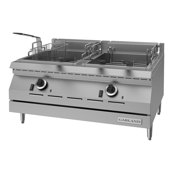 A stainless steel dual tank electric countertop deep fryer with control knobs and fryer baskets.