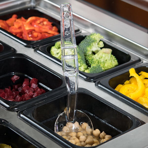 A clear plastic spoon in a container of food on a tray.