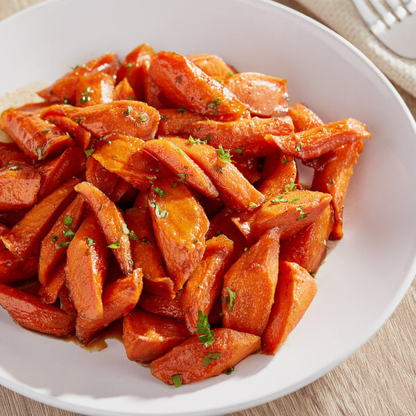 A plate of roasted jumbo carrots with herbs on it.