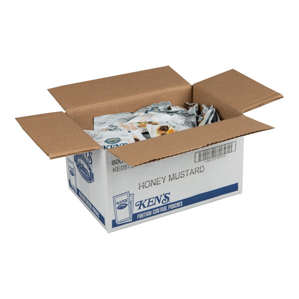 An open cardboard box containing multiple individual packets of honey mustard dressing.