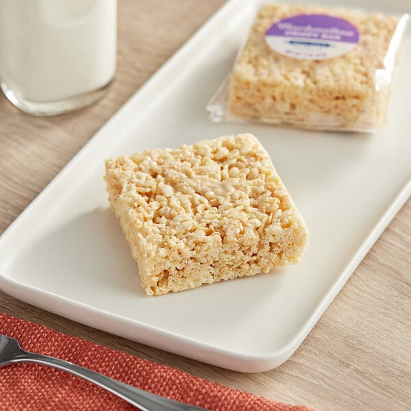 A square white rectangular Best Maid Marshmallow Crispy Bar on a plate next to a glass of milk.