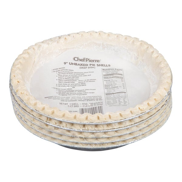 A stack of unbaked pie shells in aluminum pans with a paper label on top.