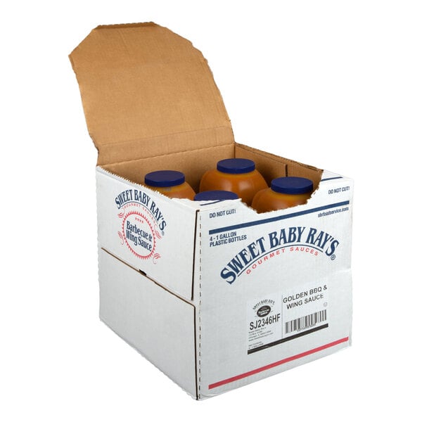 An open cardboard box containing four large plastic bottles with blue caps, labeled as Sweet Baby Ray's Golden BBQ & Wing Sauce.