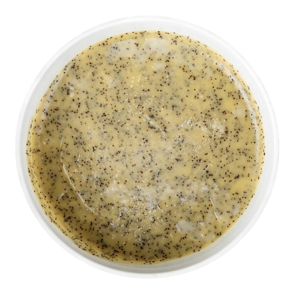 A round container filled with a yellow batter mixed with small black poppy seeds.