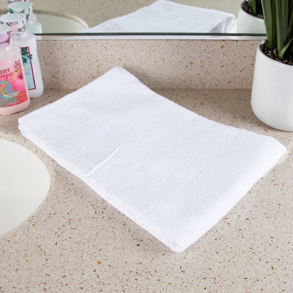 A white Oxford towel on a white counter top.