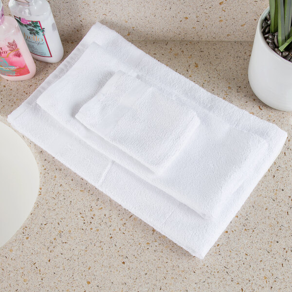 A stack of Oxford white bath towels on a white counter.