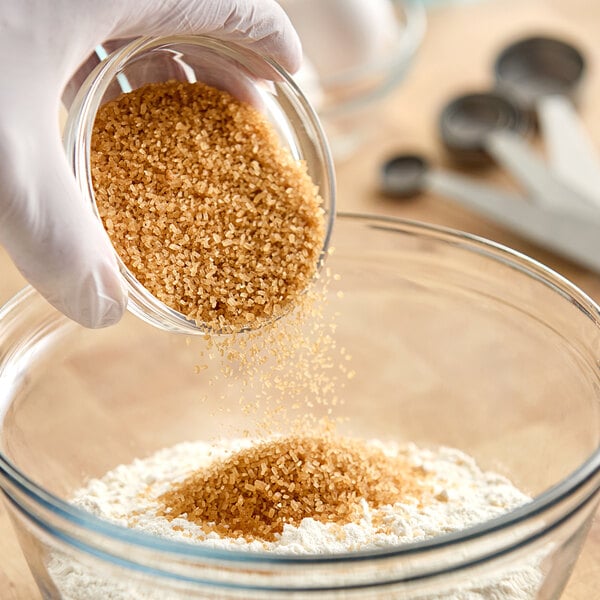 A person pouring Wholesome Sweeteners Raw Natural Demerara Turbinado Sugar into a bowl.