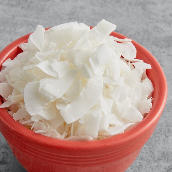 A red bowl filled with white medium chipped coconut.