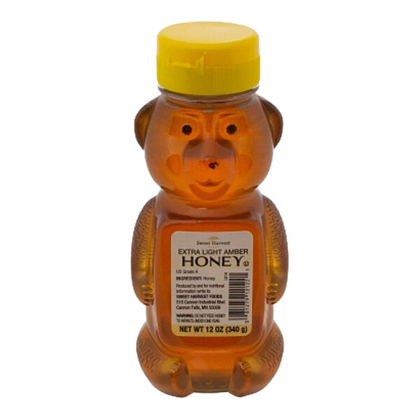 A 12-ounce plastic bear-shaped bottle of Sweet Harvest extra light amber honey with a yellow cap.