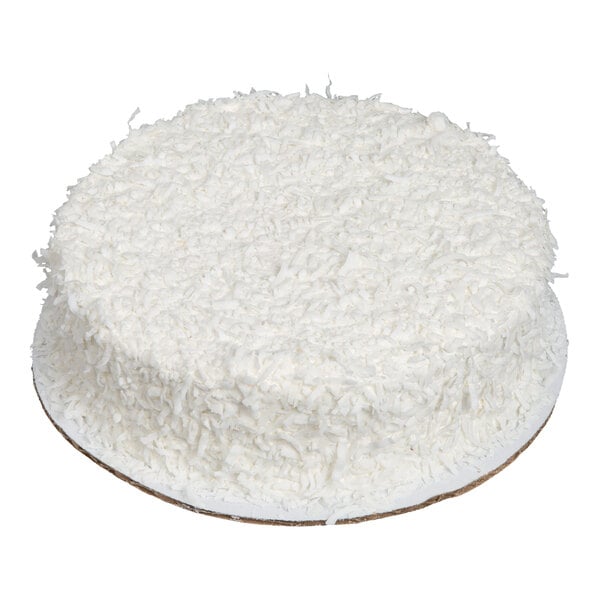 A round cake covered in white shredded coconut on the top and sides, placed on a cardboard base.