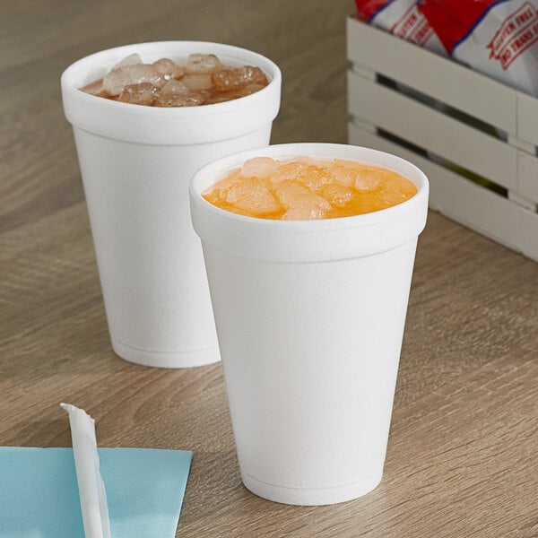 Two Dart white foam cups of beverages on a table.