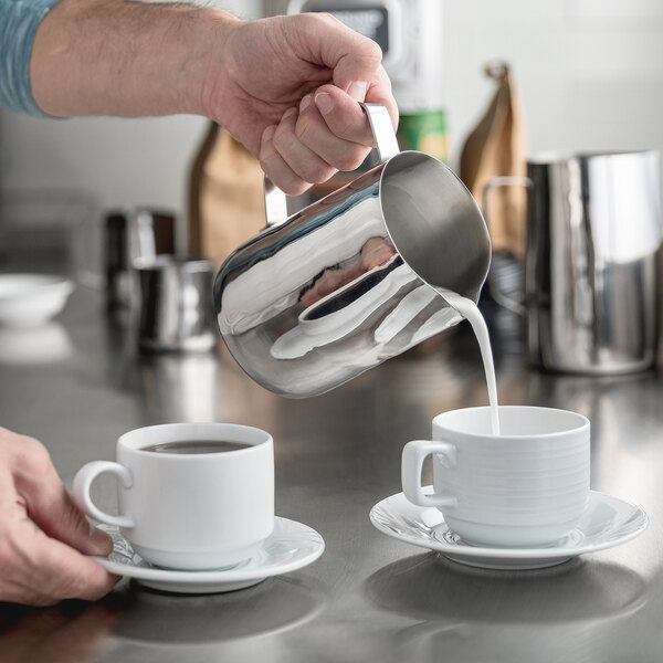 Man pouring milk into coffee for a customer