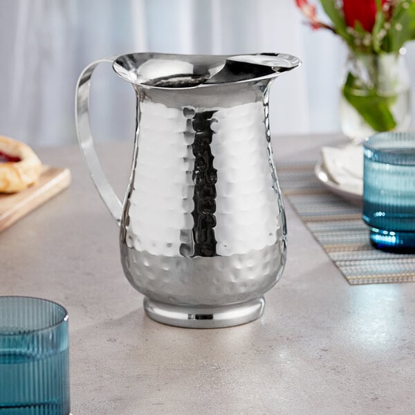 An Acopa stainless steel pitcher on a table.