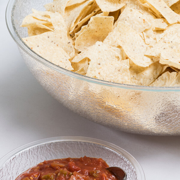 A Cambro pebbled serving bowl of chips next to a bowl of salsa.