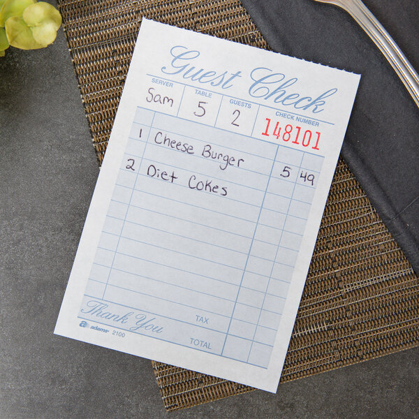 A close-up of an Adams Guest Check with writing on it.