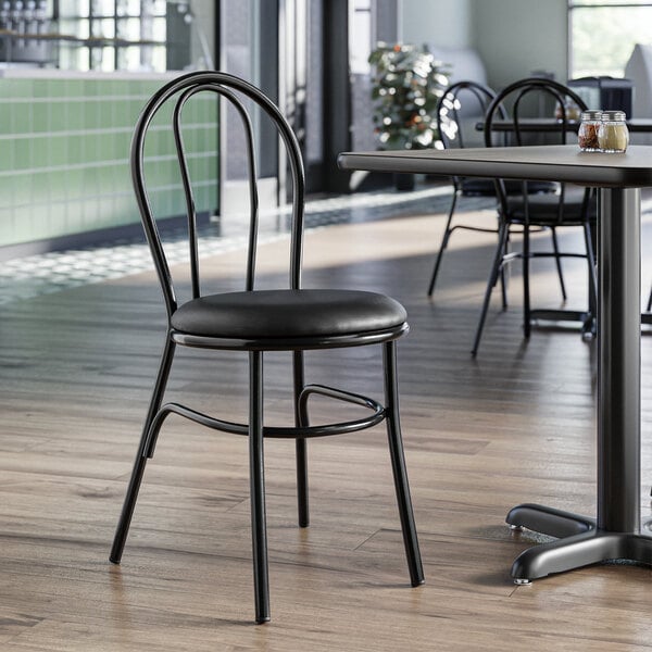 A Lancaster Table & Seating black metal hairpin chair with a black vinyl seat detached from the chair.
