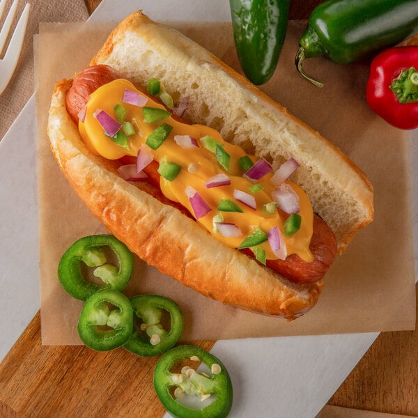 A hot dog with Muy Fresco jalapeno cheese sauce and jalapenos on a counter.