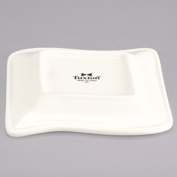 A white square Tuxton china plate with a wave design.