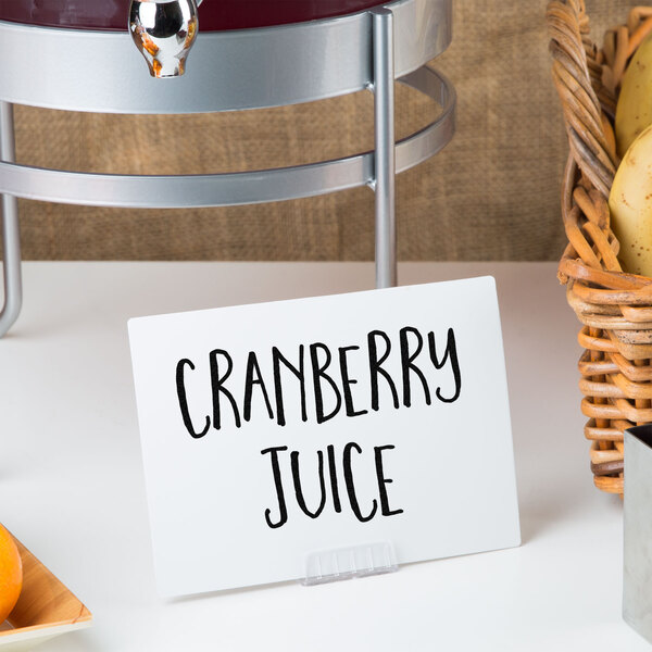 A white table with a juice dispenser and a sign with black text.