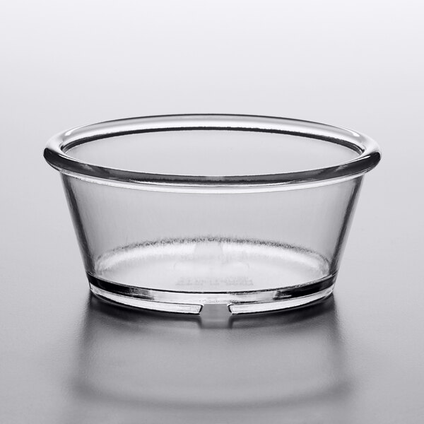 A clear plastic ramekin on a white surface.