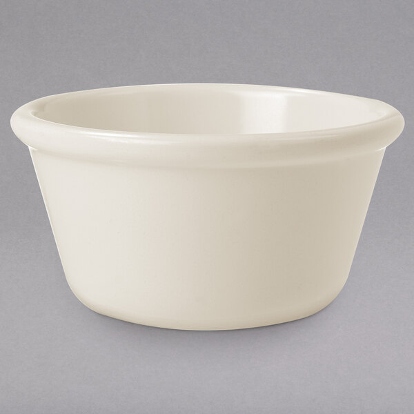 An ivory smooth melamine ramekin on a gray surface.