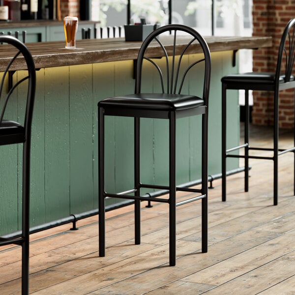 A Lancaster Table & Seating black bar stool with a black vinyl seat.