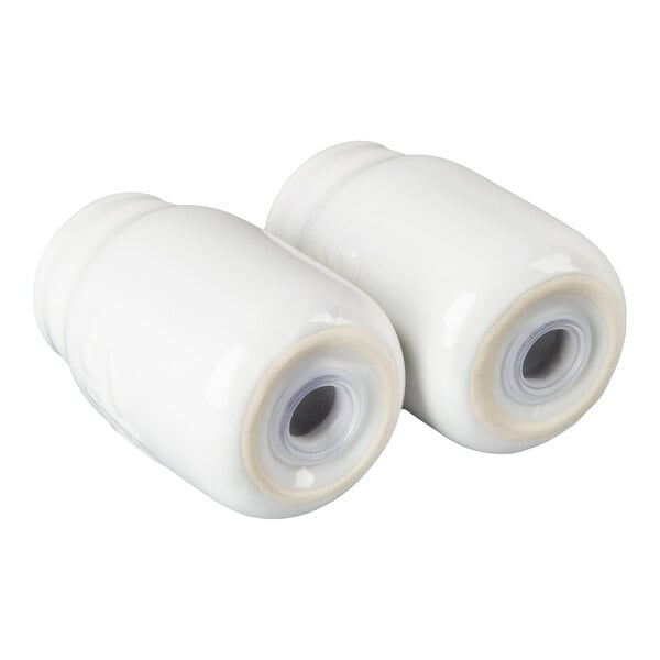 Two small, white, ceramic containers with round openings on one end, resembling mason jars.