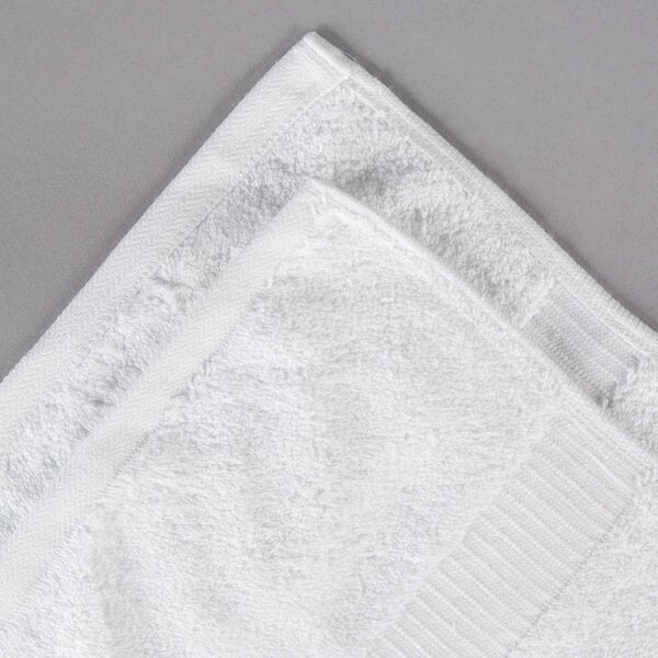 A white Oxford Belleeza bath towel on a gray surface.