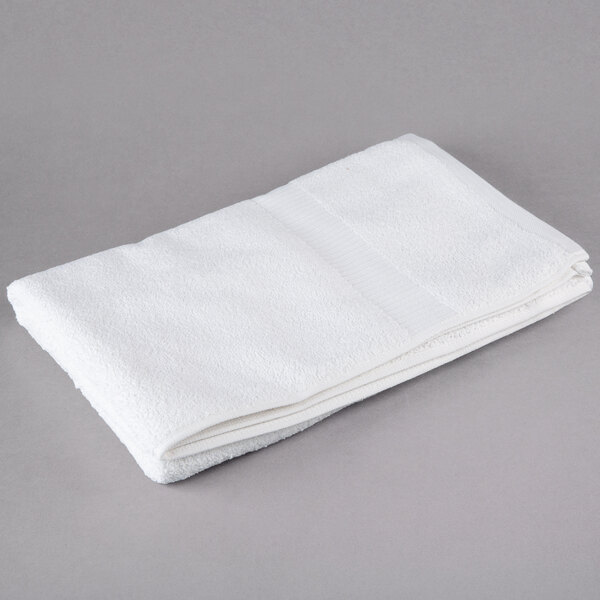 A folded white Oxford Belleeza bath towel on a gray surface.