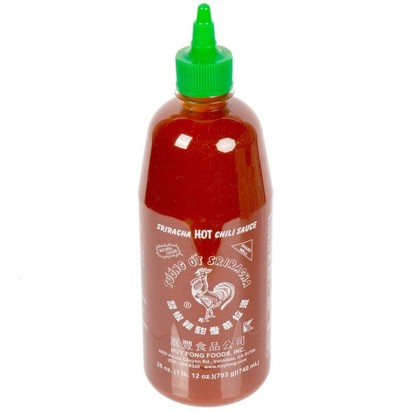 A bottle of Huy Fong Sriracha hot sauce with a green lid.