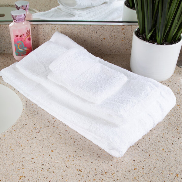 A stack of white Oxford Belleeza bath towels on a counter.