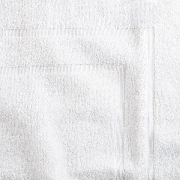 A close up of a white Oxford Platinum hotel bath mat with a square edge.