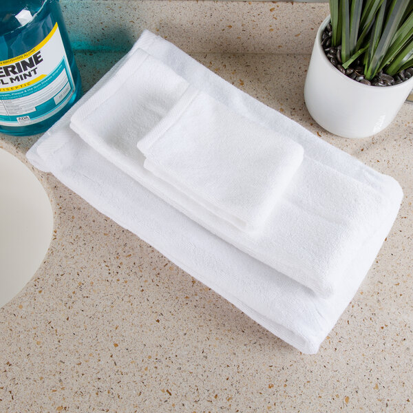 A stack of white Oxford Platinum wash cloths on a counter next to a bottle of liquid.