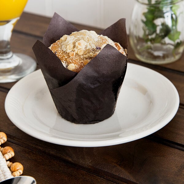 A muffin on a Oneida cream white china bread and butter plate on a table in a breakfast diner.